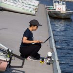 Charlene Xia, pictured at the MIT Sailing Pavilion, tests her microbiome monitoring system in the Charles River.